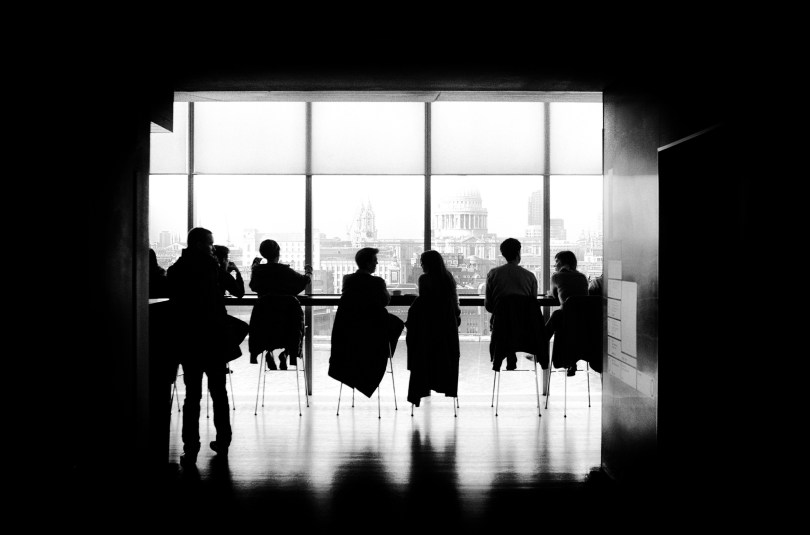 people sitting and discussing with a capitol building visible through windows in the background